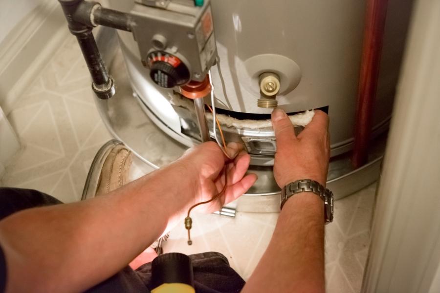 Plumber shining a flashlight on hot water heater