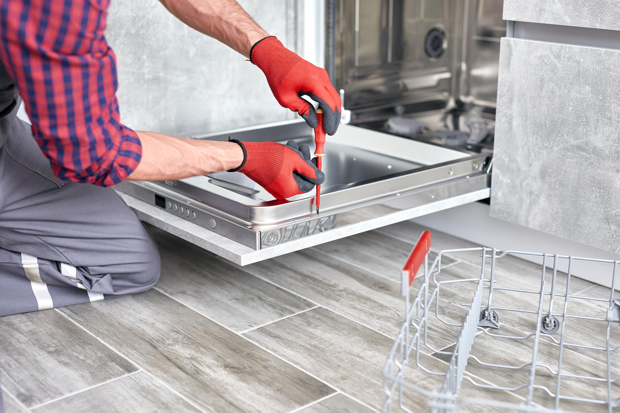 Professional plumber installing a dishwasher